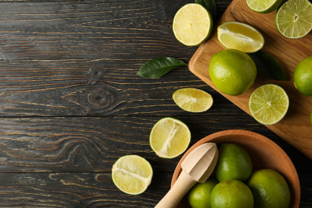 istock Bowl and board with lime on wooden background, space for text 1299761040