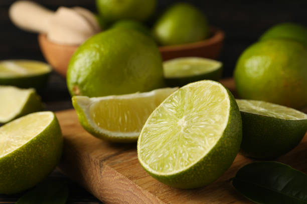 istock Bowl and board with lime on wooden background, close up 1299761193