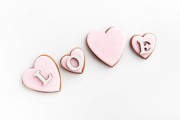 istock Gingerbread cookies in heart-shaped with white sugar icing on white background and inscription LOVE. 1299761216