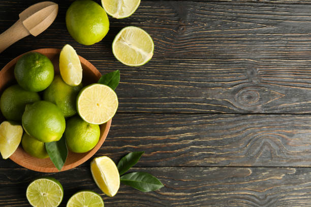 istock Bowl with ripe lime on wooden background, space for text 1299761320