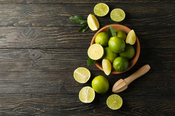 istock Bowl with ripe lime on wooden background, space for text 1299761387