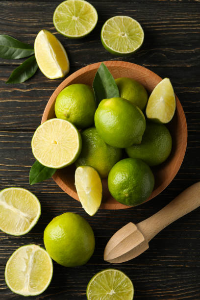 istock Bowl with ripe lime on wooden background, top view 1299761412