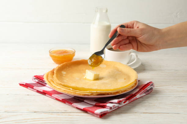 istock Female hand pour jam on crepe rolls on white wooden table 1299762878