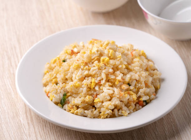 istock Chinese fried rice in white plate on bright wooden table background. 1299763163