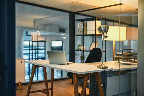 This is where you'll work the nightshift Shot of a laptop on a table in an empty office at night office cubicle no people stock pictures, royalty-free photos & images