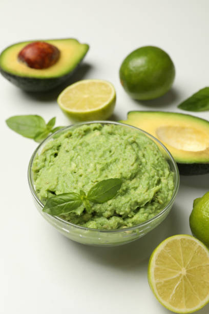 istock Bowl of guacamole, avocado, lime and basil on white background 1299764197