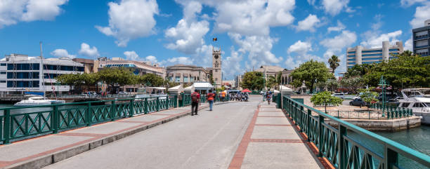 Street view and bridge in city centre of Bridgetown, Barbados. Parliament building in the background. Blue sky and white clouds. Bright and wide image.