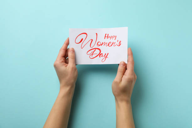 istock Female hands hold card with text Happy Women's Day on blue background 1299766382