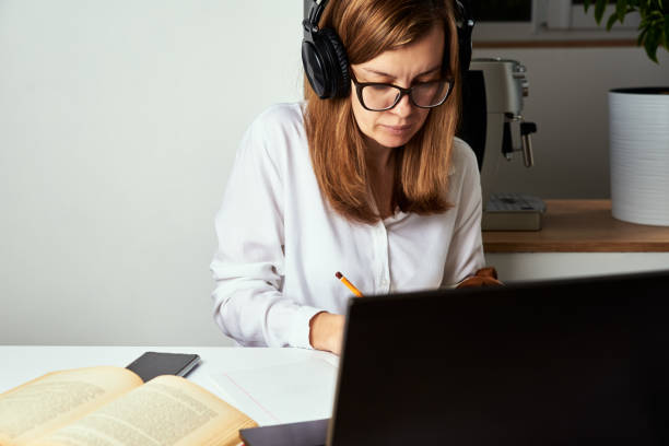 istock Remote work. Online course, distance education and e learning concept. Woman in headphones listen audio course at laptop 1299766834