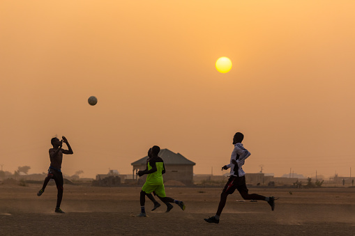 Kids playing football at sunset in Maroua