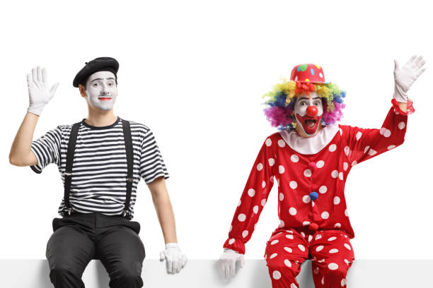 istock Funny clown and a mime sitting on a panel and waving 1299768273