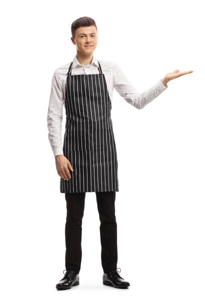 istock Young male waiter with an apron welcoming with hand 1299768285