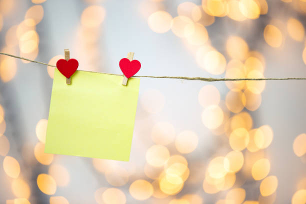 istock Blank Yellow sticky note hanging with red hearts with bokeh background, romantic Valentines day concept background copy space 1299769120