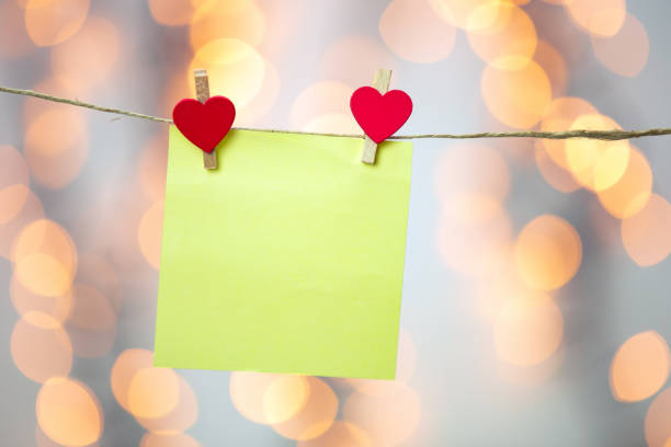 istock Blank Yellow sticky note hanging with red hearts with bokeh background, romantic Valentines day concept background copy space 1299769142