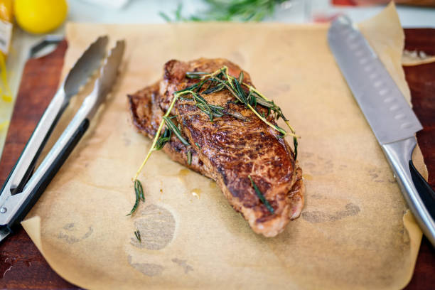 Grilled striploin sliced steak on cutting board over stone table