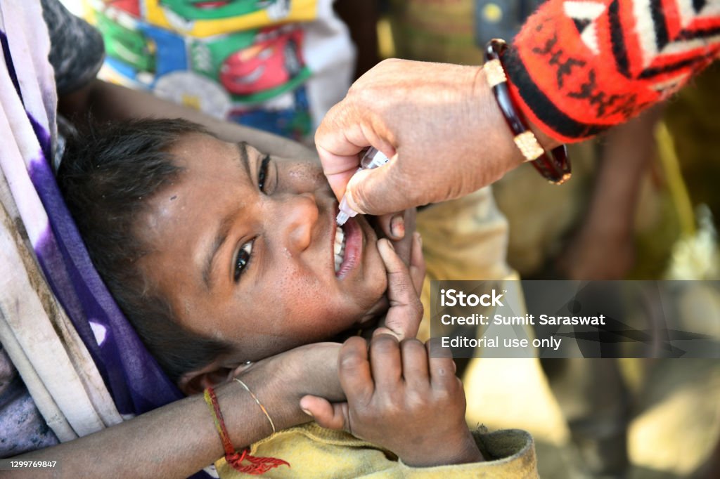 Pulse Polio Eradication Program in Rajasthan, India Beawar, Rajasthan, India, Feb. 01, 2021: An Anganwadi health worker administers polio vaccine drops to a child at a slum area during Pulse Polio eradication program in Beawar Polio Stock Photo