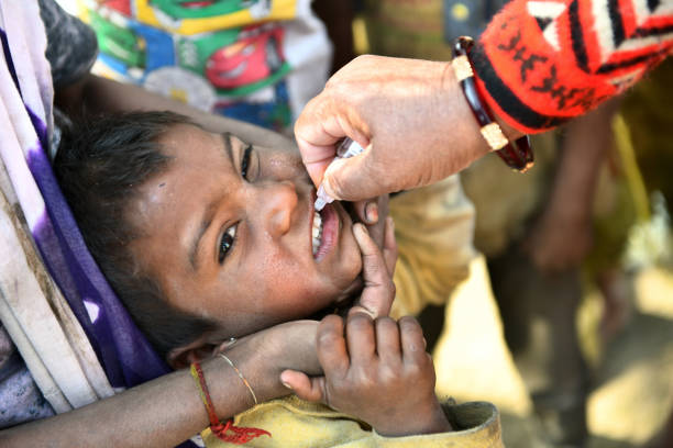 Pulse Polio Eradication Program in Rajasthan, India Beawar, Rajasthan, India, Feb. 01, 2021: An Anganwadi health worker administers polio vaccine drops to a child at a slum area during Pulse Polio eradication program in Beawar polio vaccine stock pictures, royalty-free photos & images