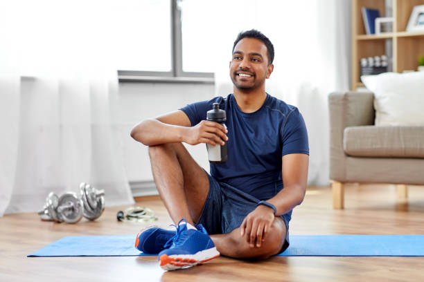 indischer mann trinkwasser nach dem training zu hause - drinking water drink men stock-fotos und bilder