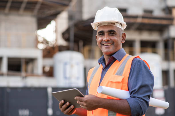 ingeniero en el sitio de construcción, utilizando tableta digital - building engineering fotografías e imágenes de stock