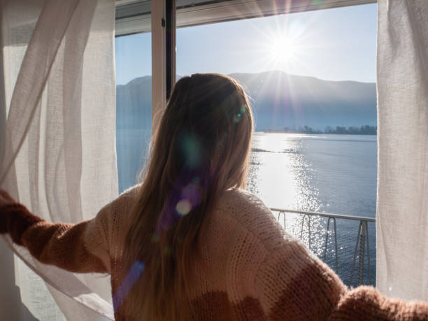 donna apre tende all'alba, nuovo inizio nuovo giorno - waking up window women morning foto e immagini stock