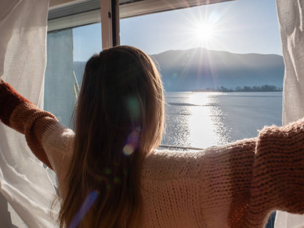 istock Female opens curtains at sunrise, new beginning new day 1299775300