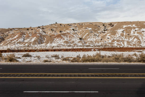 istock Rolling hills with light snow next to empty highway in rural New Mexico on cloudy day 1299775443
