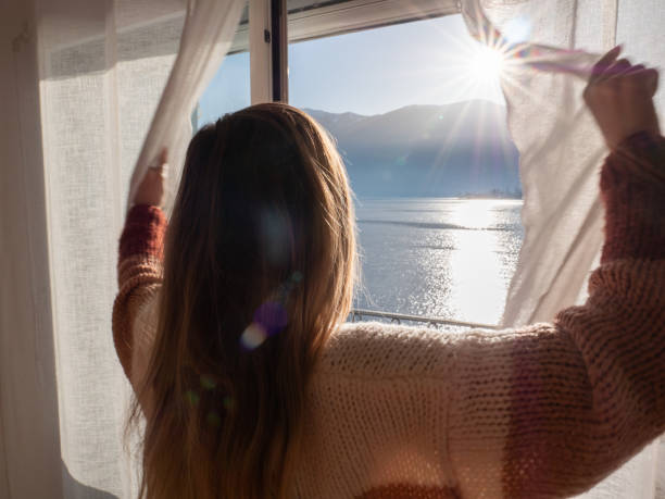 istock Female opens curtains in the morning, lake view 1299775501