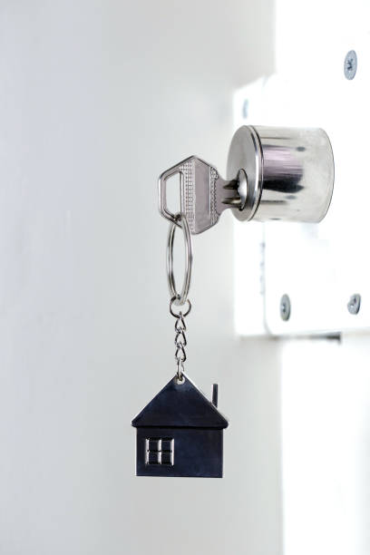 silver house key in white door, with little keychain house, opening door to new house, home, investment, real estate concept, space for text - key real estate key ring house key imagens e fotografias de stock