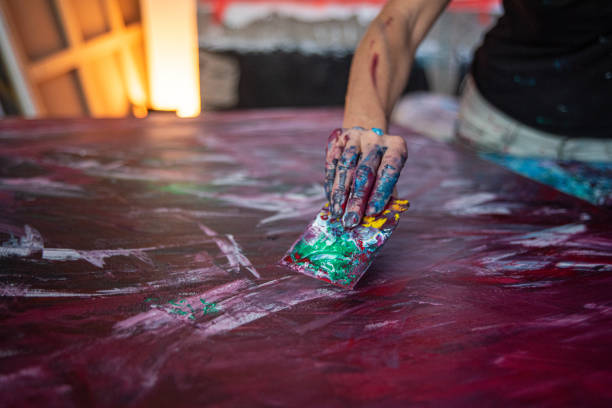 you can see the hand of a young woman painter with a tool she uses to paint pictures in her studio, focus on hands stock photo