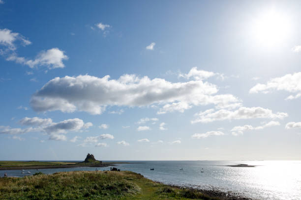 holy island castle blick von der küste mit blauem himmel - northumberland england lindisfarne northeastern england england stock-fotos und bilder