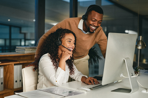 Shot of two call centre agents working together in an office at night