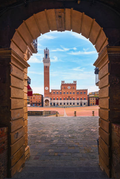 Siena, Piazza del Campo square and Mangia tower. Tuscany, Italy Siena, Piazza del Campo square, Torre del Mangia tower and Palazzo Pubblico building. Arch as a frame. Tuscany, Italy. torre del mangia stock pictures, royalty-free photos & images