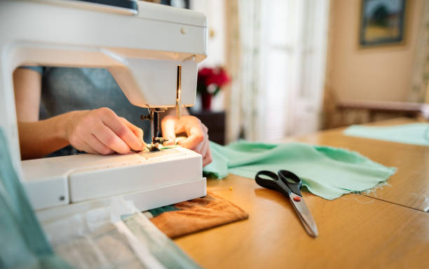 istock Woman using a sewing machine at a table in her home 1299780884