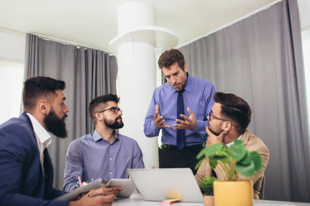 istock Colleagues at meeting in boardroom, sitting at table together, sharing ideas, discussing project strategy. 1299782776
