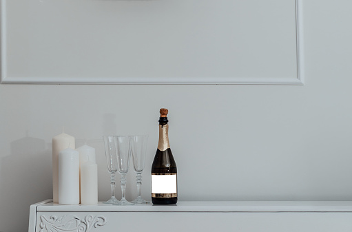 Still life shot of a bottle of champagne along side two champagne flutes indoors