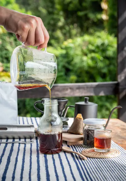 Photo of Barista pouring hot coffee after brewed to glass bottle.