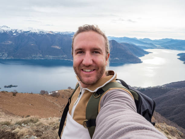 istock Cheerful young man taking a selfie portrait on mountain top 1299785429