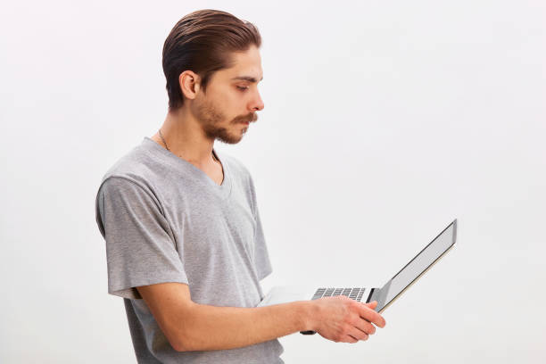 istock Portrait of a cheerful man using laptop computer over gray background 1299785794