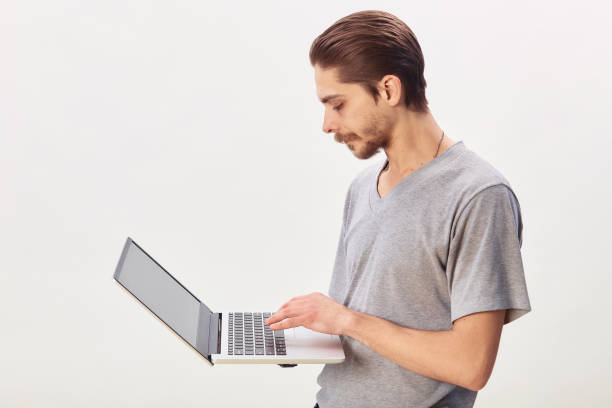 istock Portrait of a cheerful man using laptop computer over gray background 1299785801