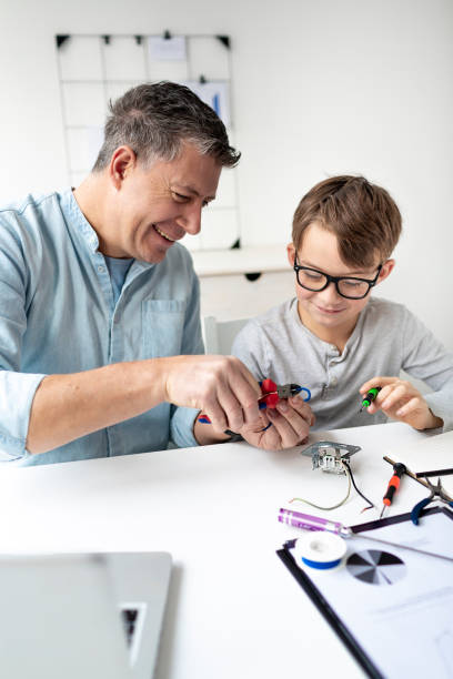 istock Father and son work at an electrical outlet while sitting at a desk. Learn for life concept 1299785878