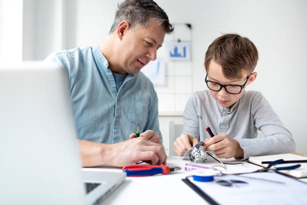 istock Father and son work at an electrical outlet while sitting at a desk. Learn for life concept 1299785887