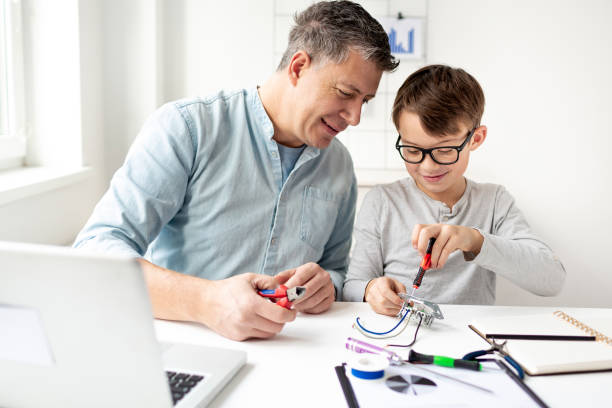 istock Father and son work at an electrical outlet while sitting at a desk. Learn for life concept 1299785997