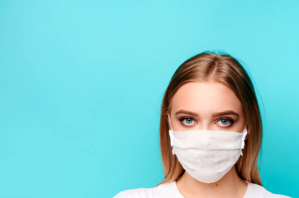 istock Young woman in a protective mask on an isolated background looking in camera 1299788237