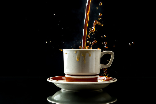 High-speed photo of hot coffee pouring into a cup as it makes a messy splash