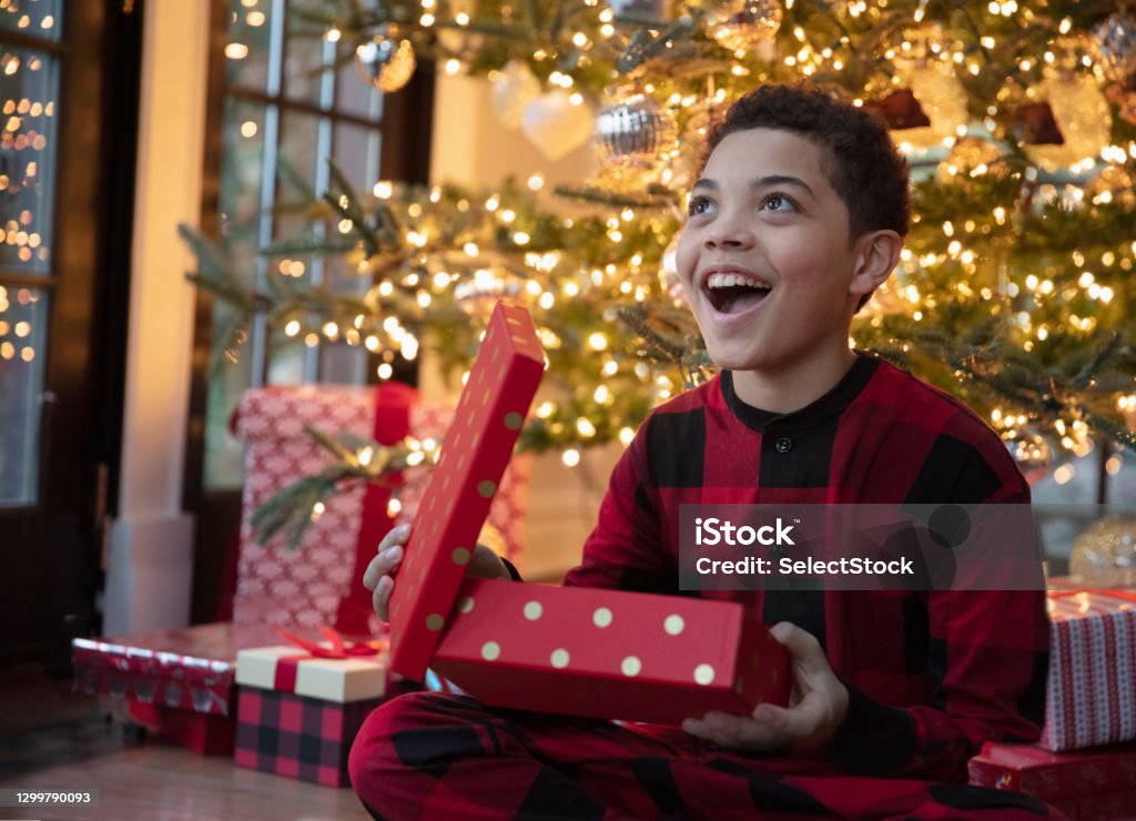 Mixed race teenager boy opening Christmas presents Child Stock Photo