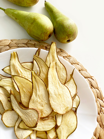 Sliced dried pieces, chips and whole fresh pear. Flat lay, top view