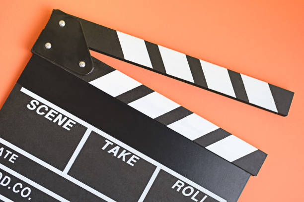 istock Filmmaker profession. Clapperboard on ogange background top view. 1299793278