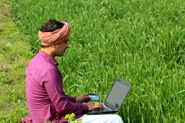istock indian farmer sitting using laptop and bank card,wheat field 1299796628