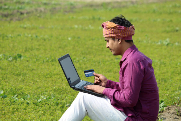 istock happy indian farmer using laptop and bank card 1299796755