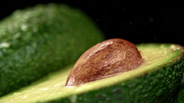 SLO MO TD Water sprinkling over a half of an avocado